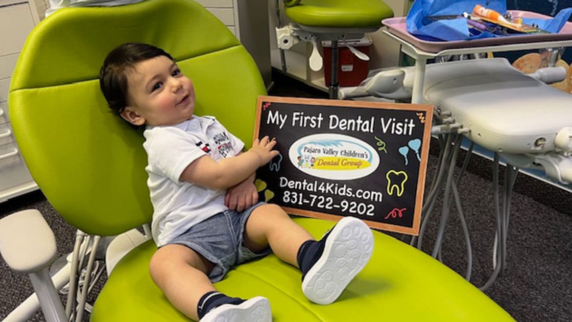Child in dentist chair with first visit sign